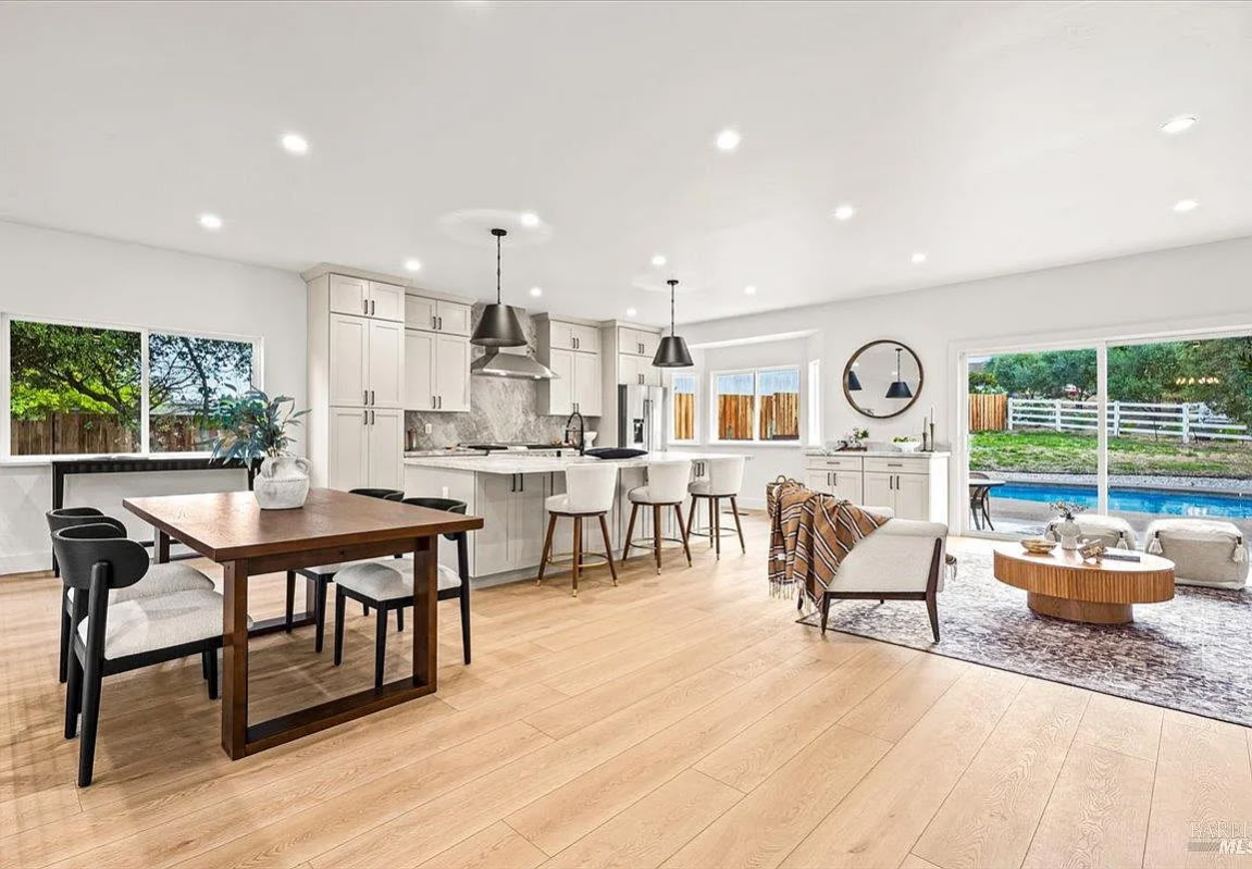 Open kitchen, dining, and living area staged with neutral furniture