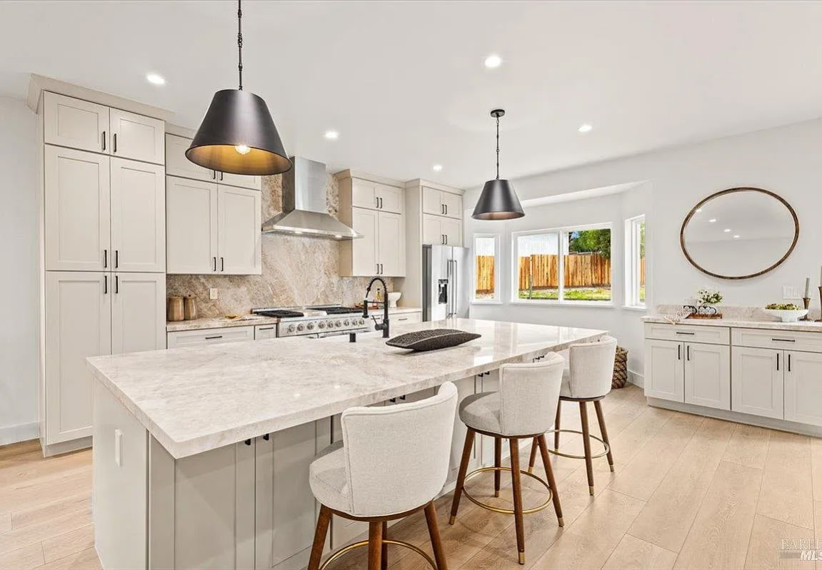 Bright staged kitchen with marble island and neutral bar stools