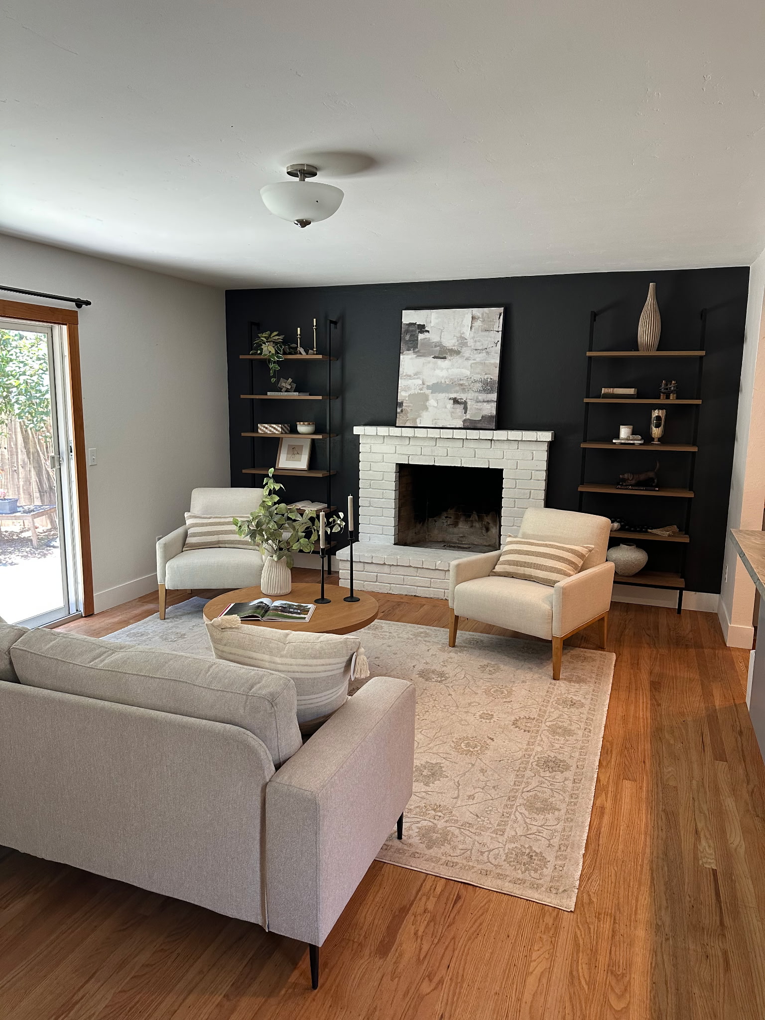 Living room staged around a white brick fireplace and black feature wall